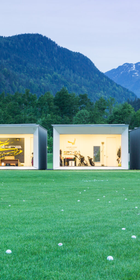 Tiny Houses auf einer grünen Wiese vor einer Berglandschaft