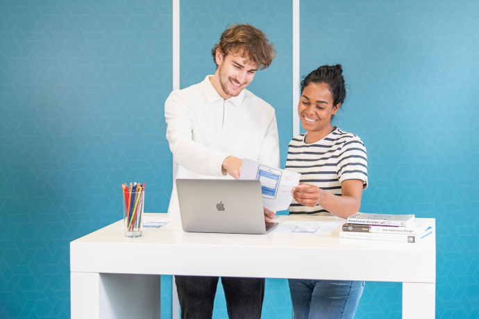 Zwei Menschen schauen auf einen Laptop