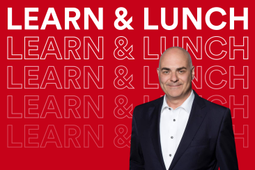 Stefan Metzger im dunklen Anzug mit weissem Hemd vor rotem Hintergrund mit dem wiederholten Schriftzug «Learn & Lunch».